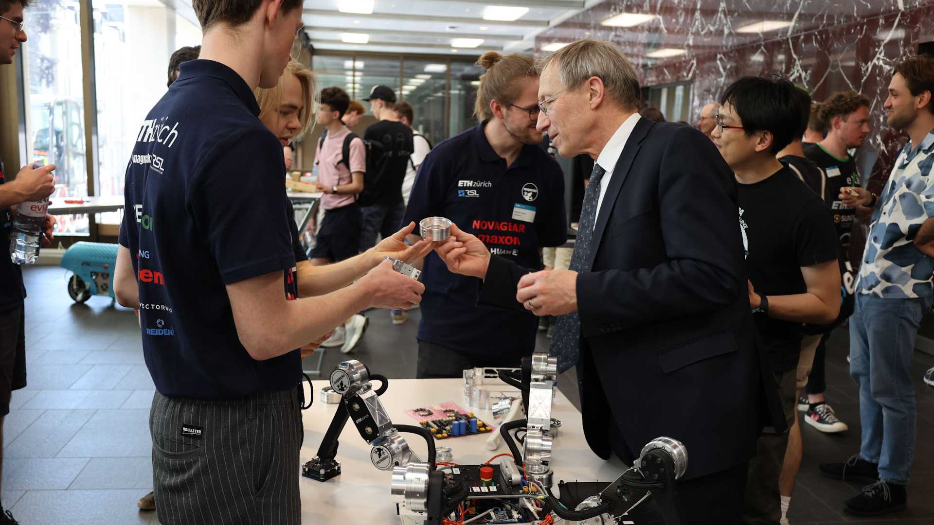 Professor Wegener admires a single component at the booth, other guests are in the background