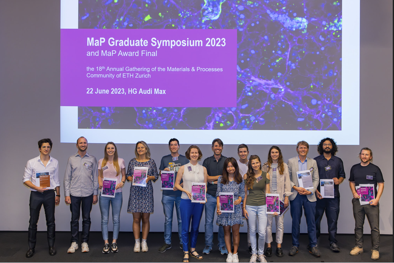 Group of MaP awardees in front of the powerpoint slide showing the official MaP Graduate Symposium banner